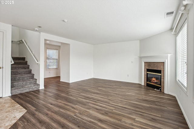 unfurnished living room featuring a tiled fireplace and dark hardwood / wood-style flooring