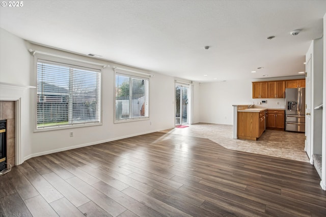 unfurnished living room with sink, a fireplace, and light hardwood / wood-style floors