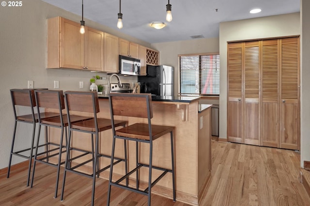 1040 NW Naito Pkwy Unit O-10, Portland, OR 97209 - kitchen with stainless steel appliances, light brown cabinets, a peninsula, light wood-type flooring, and recessed lighting