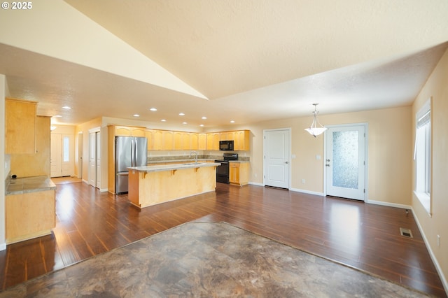 kitchen featuring vaulted ceiling, a breakfast bar, decorative light fixtures, a center island, and black appliances