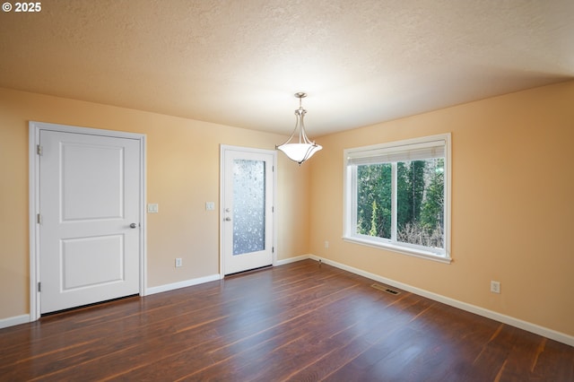 empty room with dark hardwood / wood-style floors and a textured ceiling