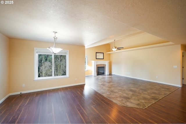 unfurnished living room with ceiling fan, dark wood-type flooring, a textured ceiling, and vaulted ceiling