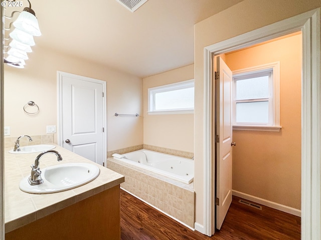 bathroom with vanity, tiled tub, and hardwood / wood-style flooring