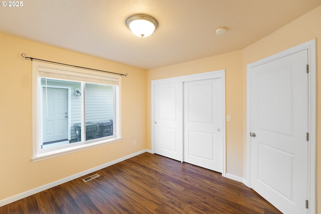 unfurnished bedroom with dark wood-type flooring and a closet