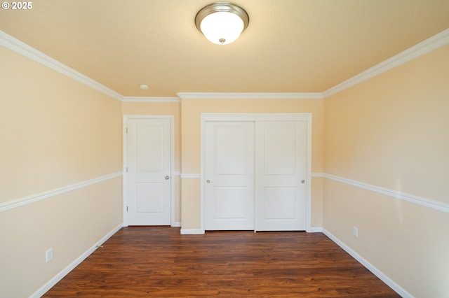 unfurnished bedroom featuring dark wood-type flooring, ornamental molding, and a closet