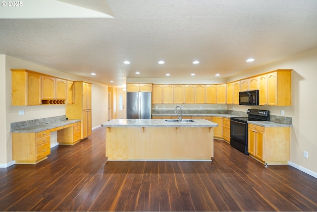 kitchen with sink, a kitchen island with sink, dark hardwood / wood-style floors, built in desk, and black appliances