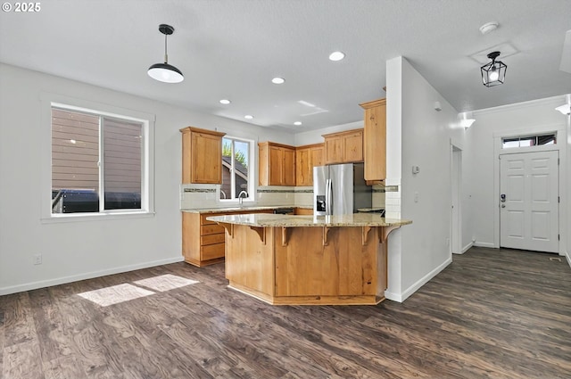 kitchen with tasteful backsplash, dark wood finished floors, stainless steel fridge with ice dispenser, baseboards, and a peninsula
