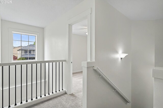 corridor featuring baseboards, carpet, and an upstairs landing