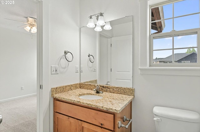 bathroom with toilet, a ceiling fan, a wealth of natural light, and vanity