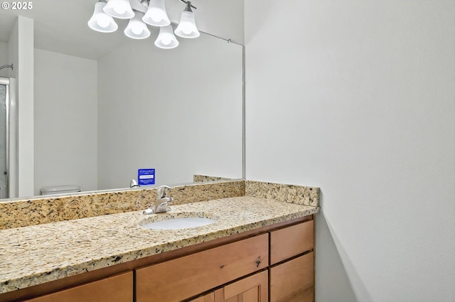 bathroom featuring vanity, a shower with door, toilet, and an inviting chandelier