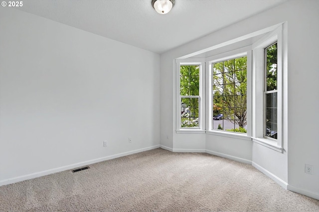 carpeted empty room featuring baseboards, plenty of natural light, and visible vents