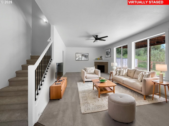 living room featuring stairs, ceiling fan, a brick fireplace, and a wealth of natural light