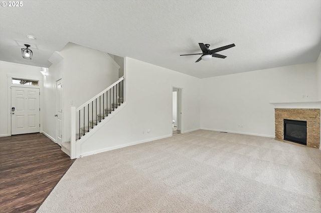 unfurnished living room with carpet flooring, a textured ceiling, a ceiling fan, baseboards, and stairway