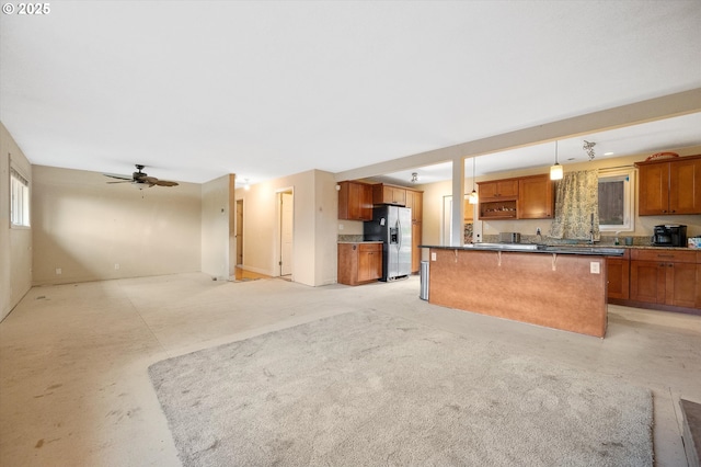 7080 SW Taylors Ferry Rd, Portland, OR 97223 - kitchen featuring stainless steel fridge, open floor plan, brown cabinetry, a kitchen island, and ceiling fan