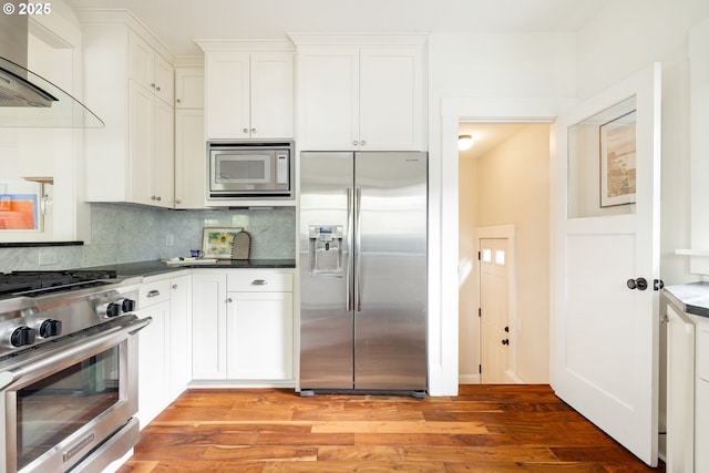 2904 NE 51st Ave, Portland, OR 97213 - kitchen with stainless steel appliances, wall chimney exhaust hood, decorative backsplash, light wood-style flooring, and white cabinets