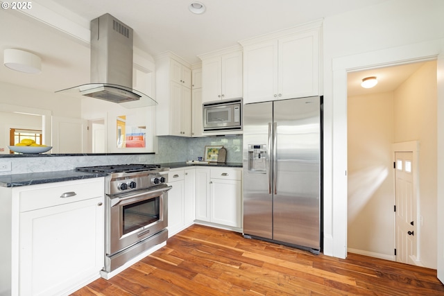 2904 NE 51st Ave, Portland, OR 97213 - kitchen with stainless steel appliances, island exhaust hood, decorative backsplash, white cabinets, and light wood-type flooring