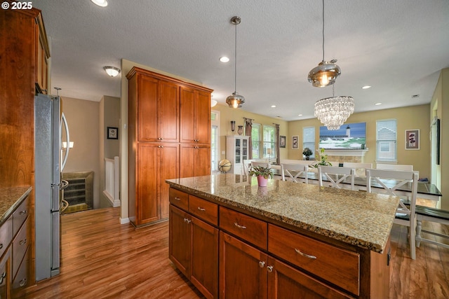2356 Benjamin Ave, Salem, OR 97304 - kitchen with freestanding refrigerator, wood finished floors, a center island, light stone countertops, and recessed lighting