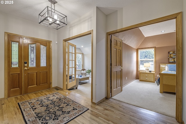 610 NE Sundance Ct, Hillsboro, OR 97124 - entrance foyer featuring light wood-type flooring, vaulted ceiling, baseboards, a chandelier, and a textured ceiling