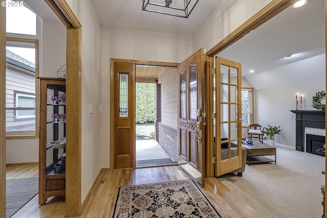 610 NE Sundance Ct, Hillsboro, OR 97124 - entrance foyer with plenty of natural light, light wood-style floors, baseboards, a fireplace, and vaulted ceiling