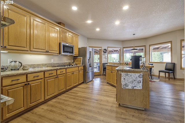 610 NE Sundance Ct, Hillsboro, OR 97124 - kitchen with stainless steel appliances, recessed lighting, a textured ceiling, light wood finished floors, and a center island with sink