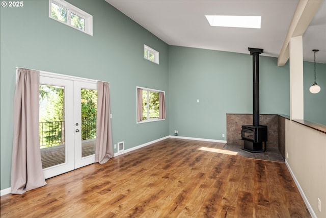 32475 Beymer Rd, Eugene, OR 97405 - unfurnished living room featuring a wood stove, a skylight, wood finished floors, french doors, and baseboards