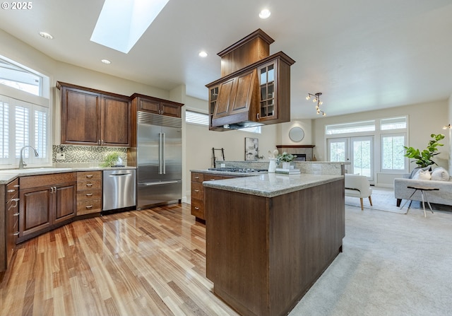 kitchen with stainless steel appliances, a skylight, a sink, open floor plan, and a wealth of natural light