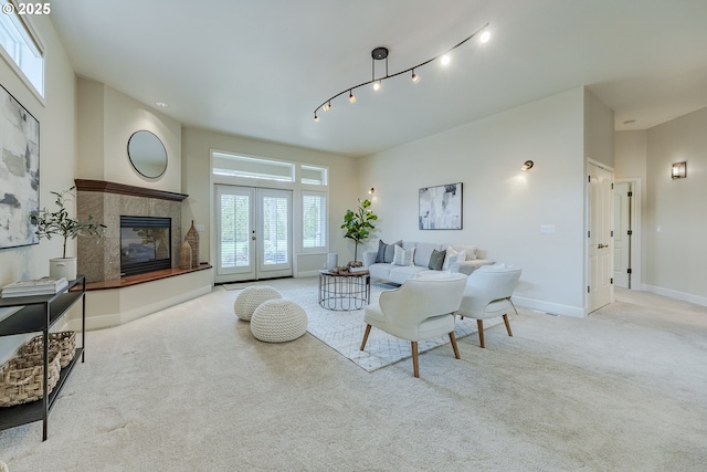 carpeted living room featuring french doors, track lighting, a fireplace, and baseboards