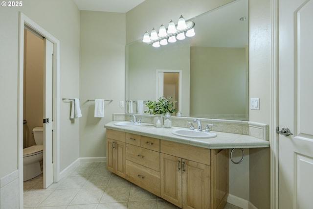 bathroom featuring double vanity, a sink, toilet, and tile patterned floors