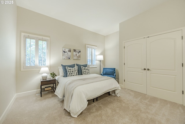 bedroom with light carpet, a closet, and baseboards