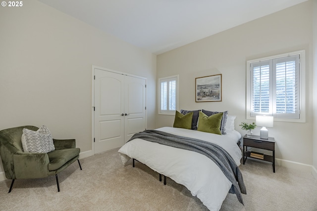 bedroom featuring a closet, light colored carpet, and baseboards