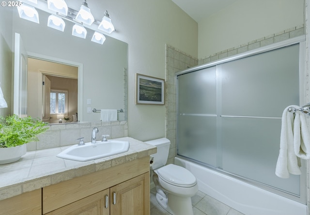 bathroom with bath / shower combo with glass door, vanity, toilet, and tile patterned floors