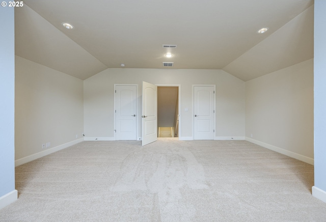 additional living space with lofted ceiling, baseboards, light carpet, and visible vents