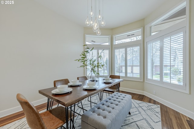 dining area with wood finished floors, visible vents, and baseboards