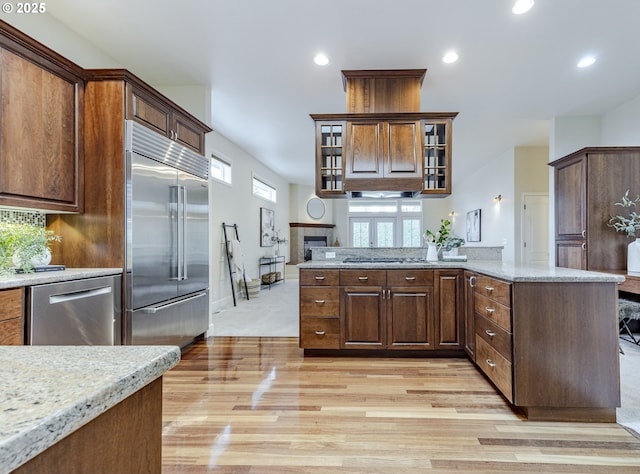 kitchen featuring glass insert cabinets, recessed lighting, appliances with stainless steel finishes, and a tile fireplace