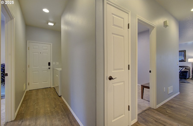 hall with dark wood-type flooring and washing machine and clothes dryer