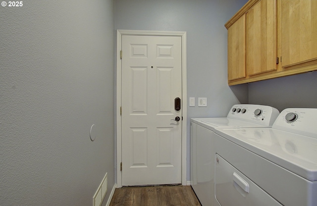 laundry area with dark wood-type flooring, cabinets, and washer and clothes dryer