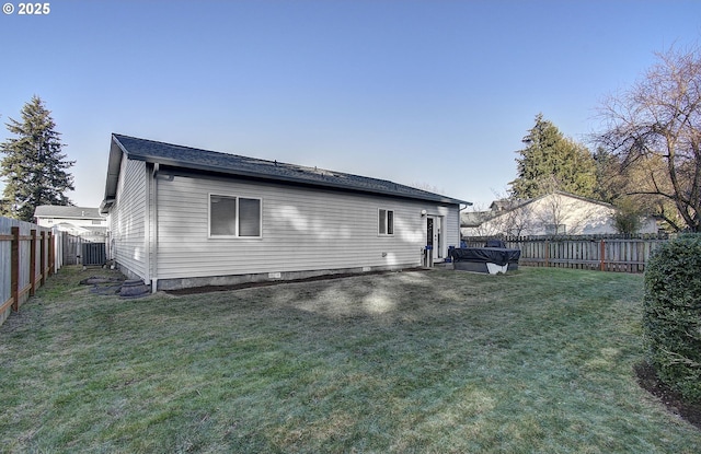 rear view of house with central air condition unit and a lawn