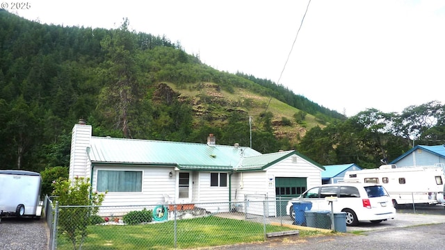 610 Bluff Rd, Klickitat, WA 98628 - ranch-style home featuring a chimney, a fenced front yard, an attached garage, and a metal roof