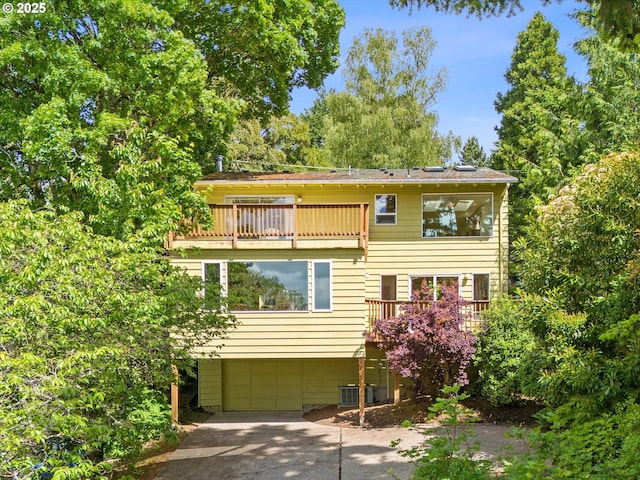 7027 SW 33rd Pl, Portland, OR 97219 - view of front facade with a garage, a balcony, concrete driveway, and central air condition unit