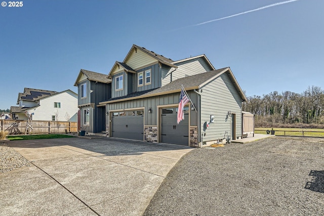 view of front of property featuring stone siding, fence, board and batten siding, concrete driveway, and an attached garage