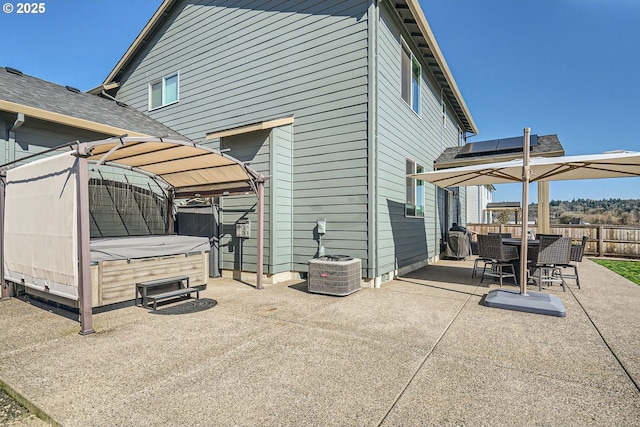 rear view of house featuring outdoor dining space, fence, solar panels, a hot tub, and a patio area