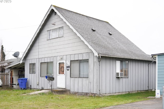 view of front of property with a shingled roof, cooling unit, a front lawn, and board and batten siding