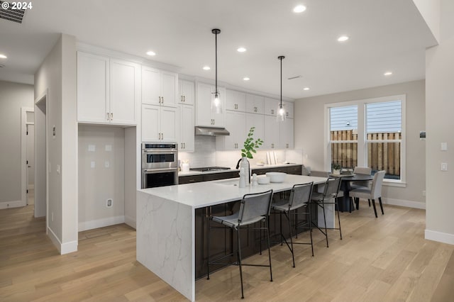 17733 NW Layla Ter Lot 6, Portland, OR 97229 - kitchen featuring baseboards, under cabinet range hood, appliances with stainless steel finishes, white cabinetry, and light wood-type flooring