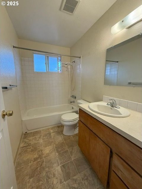 bathroom featuring lofted ceiling, toilet, visible vents, vanity, and washtub / shower combination