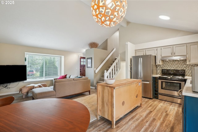 kitchen with gray cabinetry, lofted ceiling with beams, light hardwood / wood-style flooring, hanging light fixtures, and appliances with stainless steel finishes