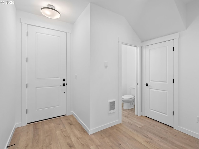 doorway featuring light wood-style flooring, baseboards, and lofted ceiling