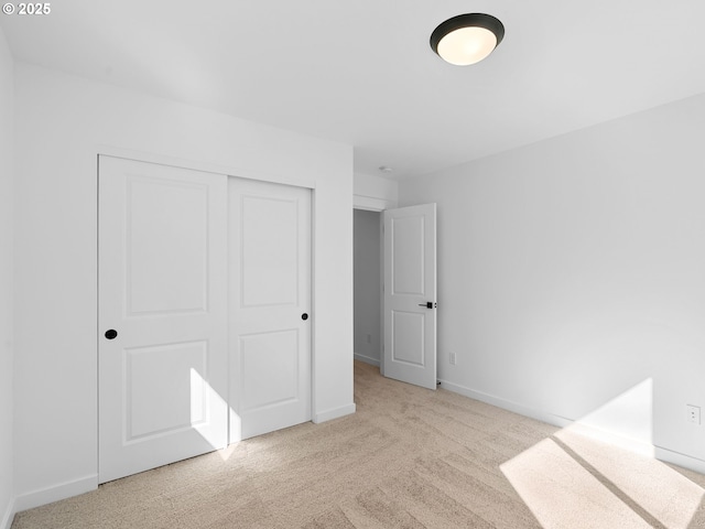 unfurnished bedroom with carpet floors, a closet, and baseboards