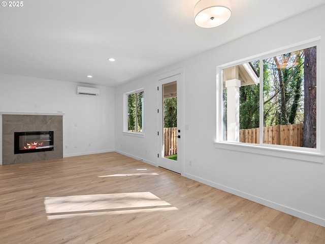 unfurnished living room featuring a wall mounted AC, healthy amount of natural light, baseboards, and recessed lighting
