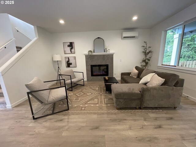 living area featuring a wall mounted AC, recessed lighting, wood finished floors, a high end fireplace, and stairway