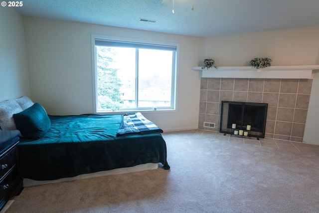 carpeted bedroom with a textured ceiling and a fireplace